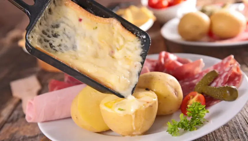 Une idée raclette originale : du fromage fondu coulant sur des pommes de terre, charcuterie et cornichons.