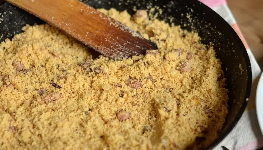 Préparation d'une recette de farine de maïs dans une poêle avec une spatule en bois.