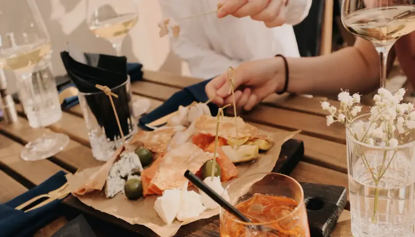 Leckereien auf einer Holzplatte, wie auf einer food pairing tabelle. Dazu Weißwein und ein Aperol Spritz.