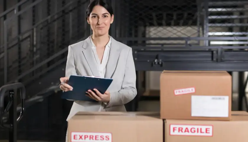 Agent celny z notatnikiem w ręku nadzoruje przesyłki, w tym oznaczone jako "EXPRESS" i "FRAGILE".