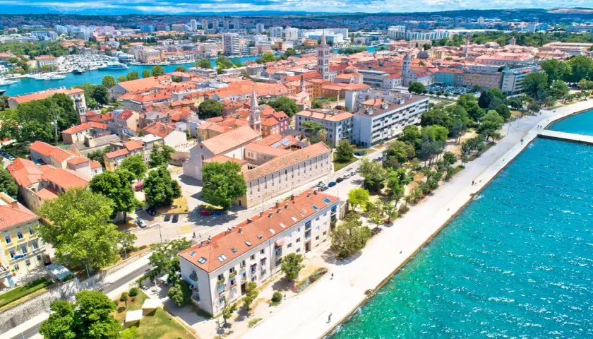 Widok na Zadar z lotu ptaka: czerwone dachy, turkusowe morze i nowoczesne budynki. Ceny w Zadarze zachęcają do odwiedzin.