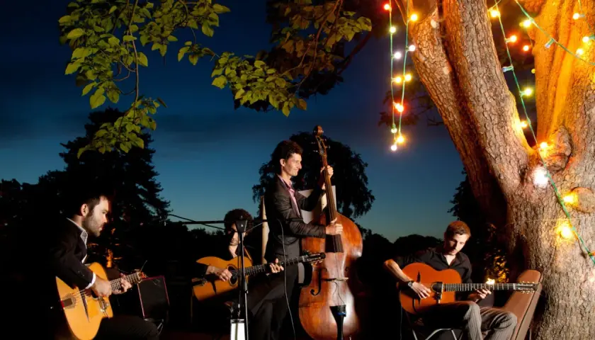 Un groupe de musique joue sous les lumières de Noël. Le contrebassiste est au centre, entouré de guitaristes. Un prix pour ce groupe de musique serait bien mérité.