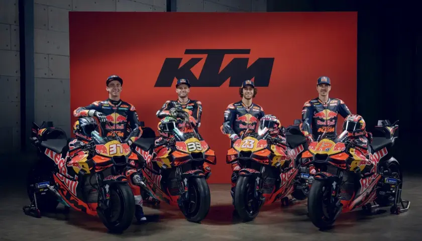 Pilotos de MotoGP KTM posan con sus motos de carreras naranjas y negras, listas para la competición.