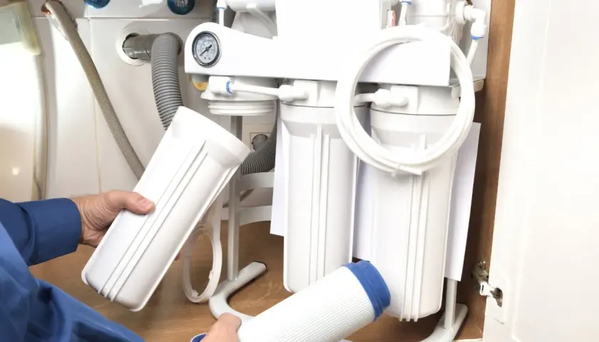 Wymiana filtra sznurkowego do wody: jak często to robić? Ręce trzymają nowe wkłady do systemu filtracji.