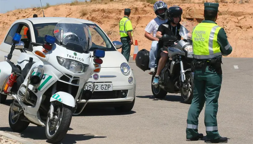 Agente de tráfico detiene a motoristas. Posible multa por llevar pasamontañas.