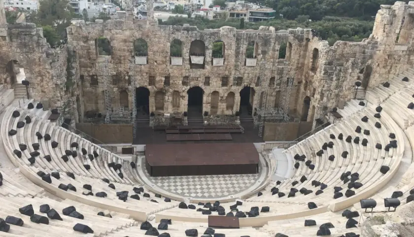 Starożytny Odeon Heroda Attyka w Atenach, z kamiennymi siedzeniami i sceną, w tle widać miasto.
