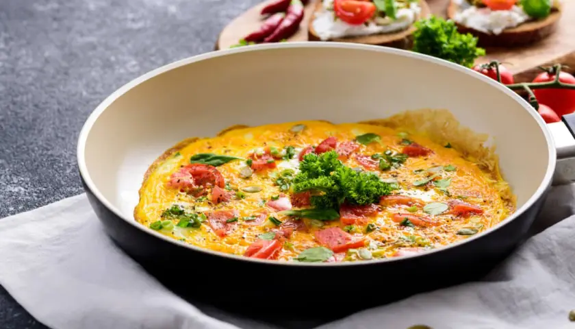 Omlet z pomidorami i ziołami na patelni. Idealny sposób, jak ograniczyć węglowodany w diecie.