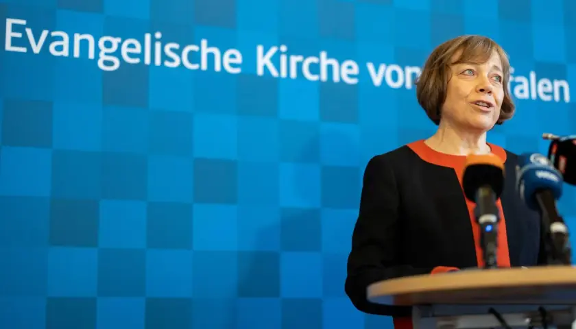 Die EKD-Vorsitzende spricht vor Mikrofonen. Im Hintergrund ist das Logo der Evangelischen Kirche von Westfalen zu sehen.