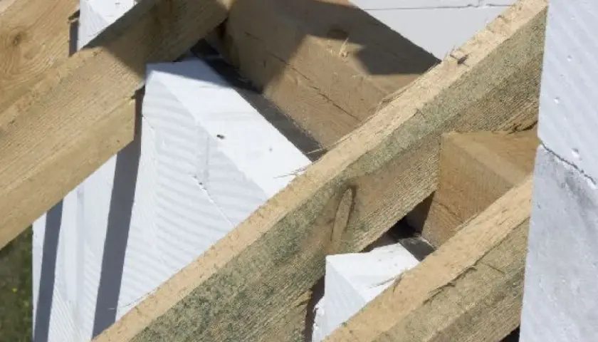 Drewniana konstrukcja dachu, w tym murłata, opiera się na białych bloczkach z betonu komórkowego.