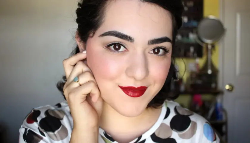 Mujer con un look de maquillaje años 40, labios rojos intensos, delineado de ojos y rubor rosado.
