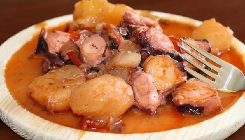 Pulpo a la mugardesa, un plato gallego con trozos de pulpo tierno y patatas cocidas en una salsa rojiza.