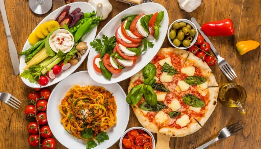 Italienische Pasta Vorspeisen: Tagliatelle Bolognese, Pizza Margherita, Caprese-Salat, Gemüsesticks mit Dip und Oliven. Ein Festmahl!