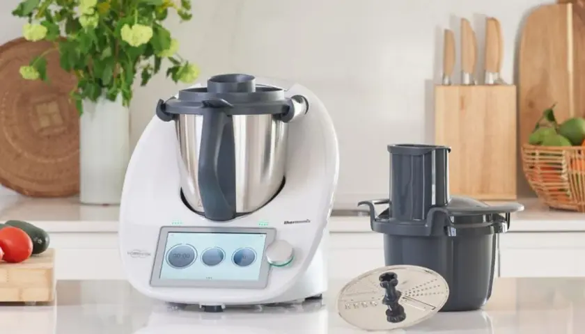 Biały Thermomix z ekranem dotykowym, akcesoriami i warzywami na blacie. Zastanawiasz się, ile wat ma Thermomix?