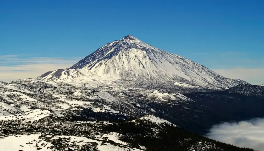 Schneebedeckter Teide-Vulkan auf Teneriffa im Dezember, ein beeindruckender Anblick über den Wolken.