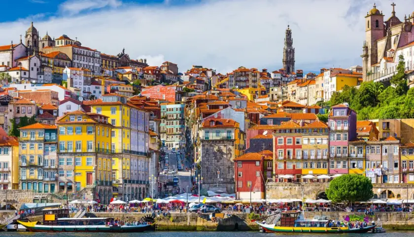 Kolorowe kamienice Porto nad rzeką, z widokiem na wieżę i kościoły. Marzenie o lotach z Gdańska do Porto.