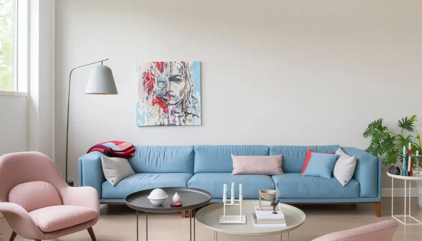 Ein hellblaues Sofa mit rosa Akzenten und einem abstrakten Gemälde. Welche Farbe passt zu altrosa? Hier wird es gezeigt.