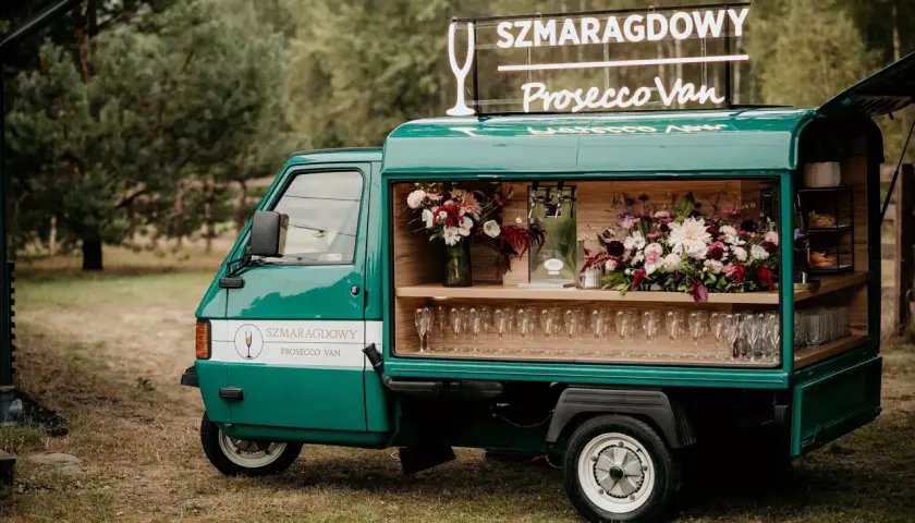Zielony Prosecco Van "Szmaragdowy" z neonem i kwiatami, gotowy na przyjęcie.