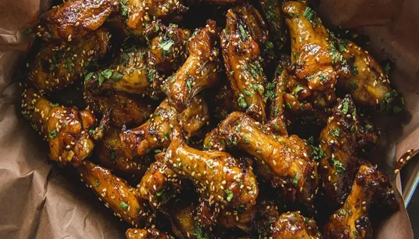 Ailes de poulet caramélisées, saupoudrées de sésame et de persil. Parfaites pour le temps de cuisson ailes de poulet sur bbq.