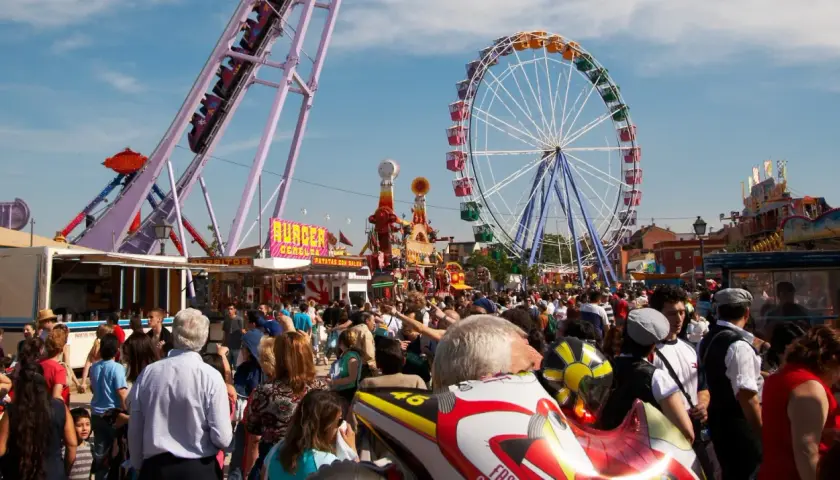 Feria en la Finca San Isidro Madrid con noria, atracciones y mucha gente disfrutando del día.