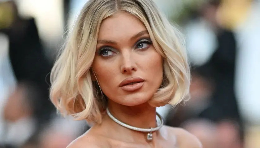 Mujer rubia con un corte de pelo estilo **italian bob**, ojos azules y un collar plateado.