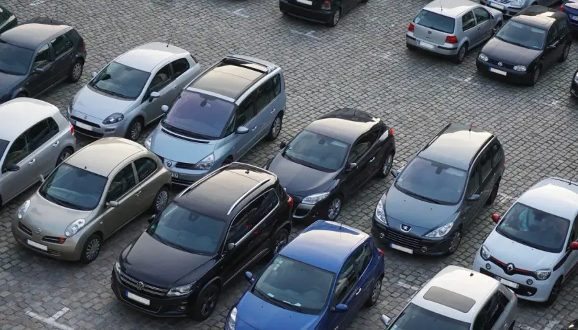 Na parkingu stoi wiele samochodów. Kto to komisant? Może to osoba, która właśnie kupuje lub sprzedaje jeden z tych pojazdów.