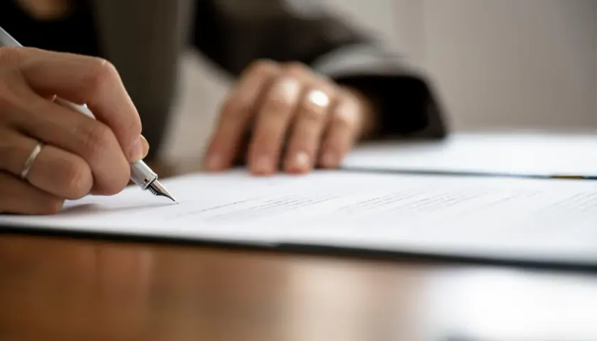 Mano firmando un contrato de arras modelo con pluma estilográfica.