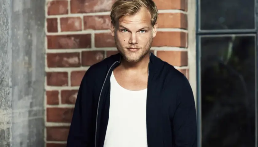 Avicii, w białej koszulce i granatowej bluzie, na tle ceglanej ściany. Jego pożegnalny list wciąż porusza serca fanów.