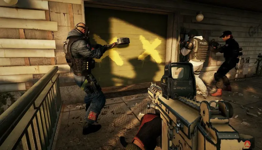 Spieler in Rainbow Six Siege mit Crossplay-Unterstützung bereiten sich auf den Kampf vor, während einer eine Wand mit gelben Kreuzen markiert.