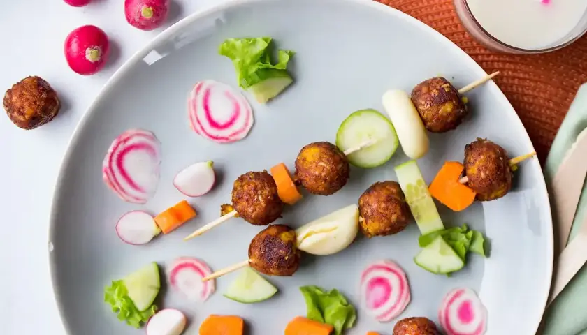 Vegetarisk mat för barn: Spett med vegetariska köttbullar, gurka, morötter och rädisor. En festlig och färgglad måltid.