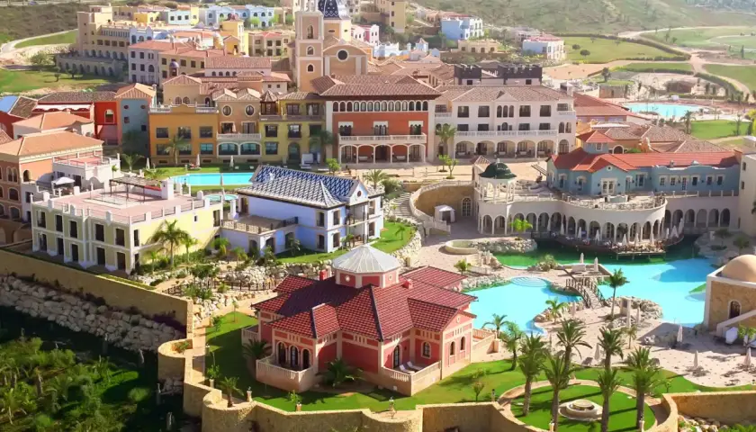 Vista aérea del hotel Villaitana en Benidorm, con sus coloridos edificios, piscinas y exuberante vegetación.
