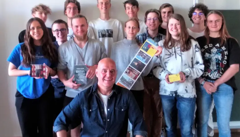 Gruppe von Schülern und einem Mann, der ein Buch von Dietmar Schultke hält.