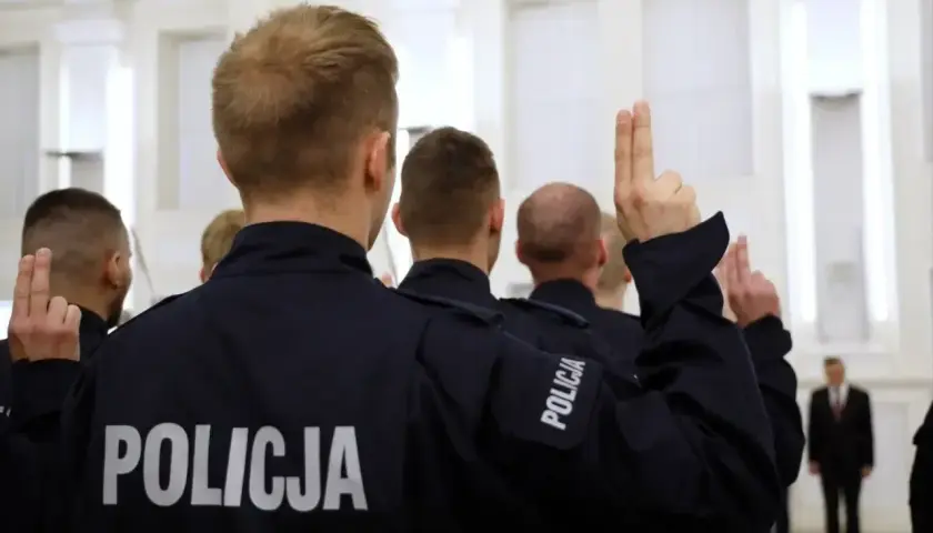 Policjanci w mundurach podnoszą ręce. Czy ich zarobki w policji są adekwatne do służby?