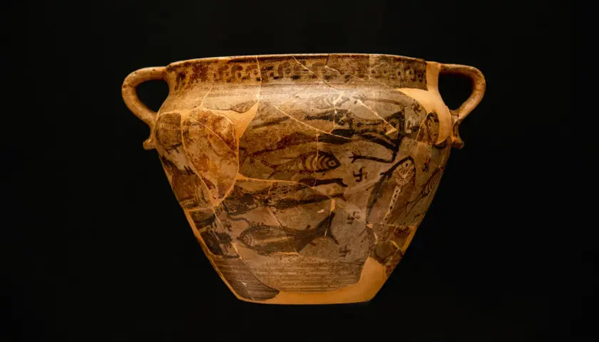 Antico vaso greco con decorazioni di pesci e figure, forse un'opera ispirata a **Giorgio Buchner**. Frammentato ma affascinante.