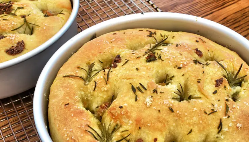 Focaccia senza glutine dorata, con rosmarino e sale grosso, appena sfornata e pronta per essere gustata.