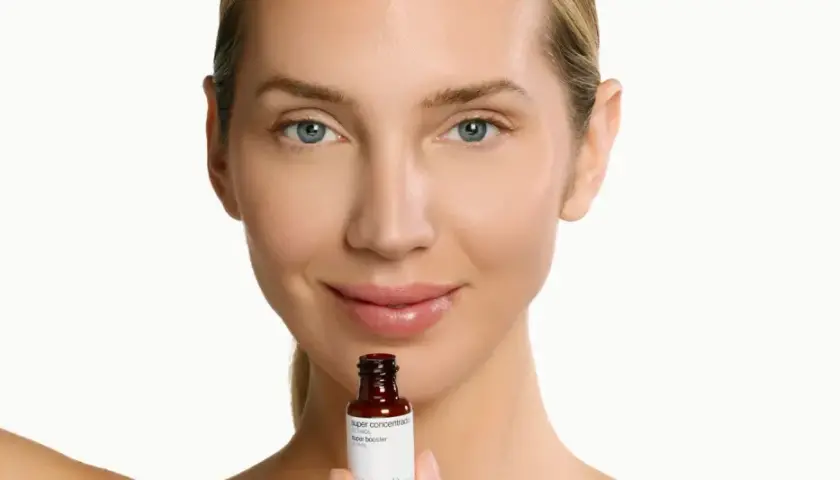 Mujer sonríe sosteniendo un frasco de sérum de retinol. Descubre para qué sirve el retinol y cómo puede mejorar tu piel.