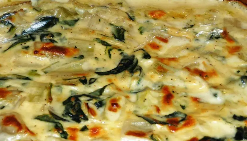 Un gratin crémeux de côte de blette, doré au four, avec des touches de vert et des bords légèrement caramélisés. Un délice réconfortant.