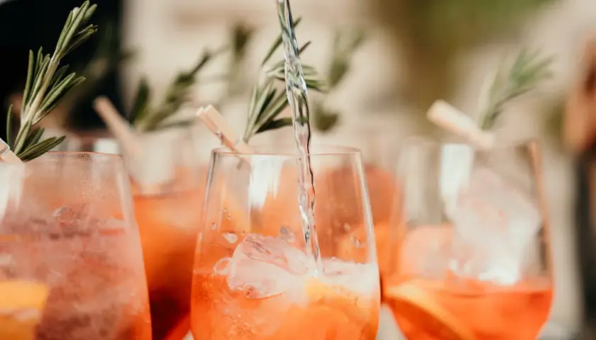 Verre de boisson soft mariage rempli de glaçons et d'une tranche d'orange, garni de romarin.