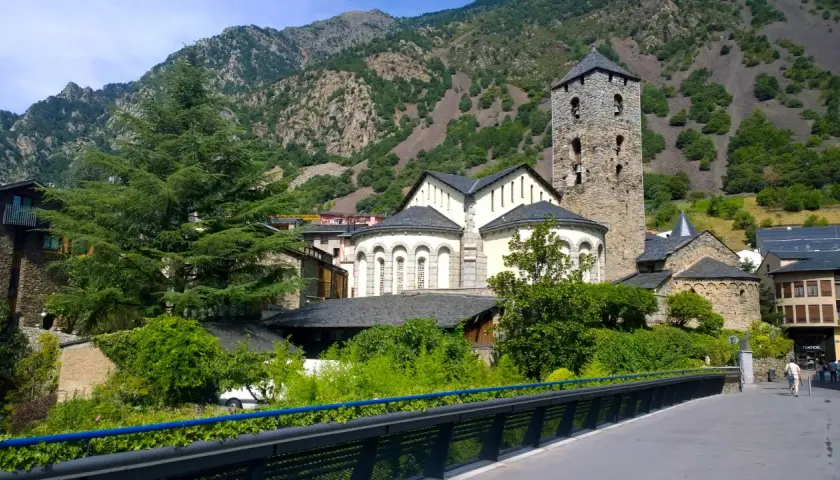 La parroquia de Escaldes-Engordany, con su torre románica, se alza majestuosa entre montañas verdes y edificios tradicionales.