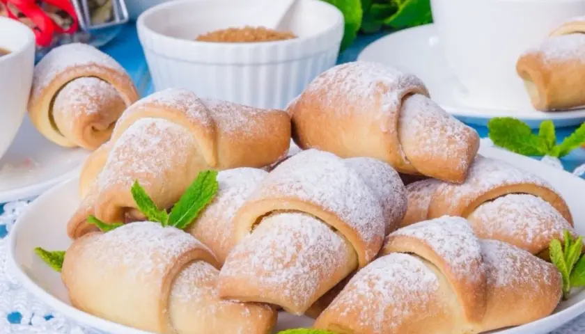 Pyszne, kruche rogaliki posypane cukrem pudrem, udekorowane listkami mięty. Idealne na deser lub do kawy.