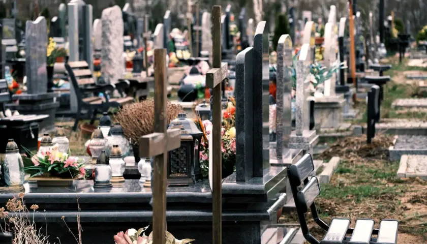 Cmentarz z nagrobkami i krzyżami. W oddali widać drzewa. Co oznacza RIP na pomniku? To skrót od łacińskiego "Requiescat in pace", czyli "Niech spoczywa w pokoju".