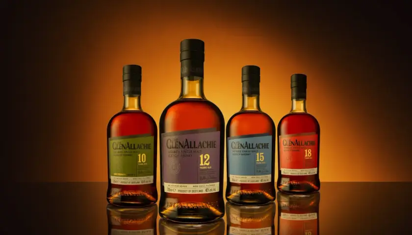 Cztery butelki whisky GlenAllachie, od 10 do 18 lat, z wyblakłymi etykietami, ukazujące skutki trzymania butelki whisky w nasłonecznionym miejscu.