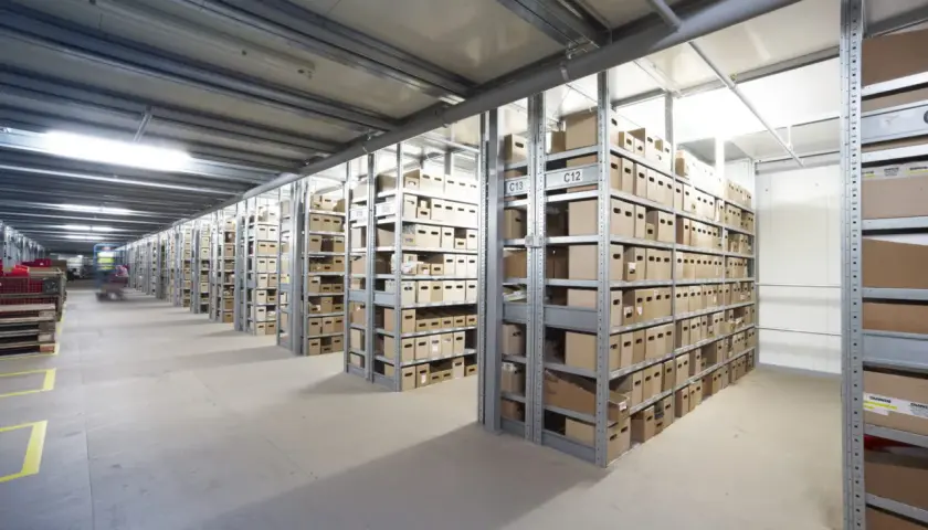 Lagerhalle mit vielen Regalen voller Kartons. Ein Gabelstapler fährt durch den Gang. Hier kann man einen Termin avisieren.