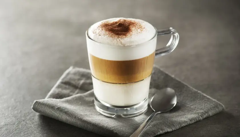 Idealne latte macchiato proporcje: mleko, espresso i pianka tworzą apetyczne warstwy. Posypane kakao.