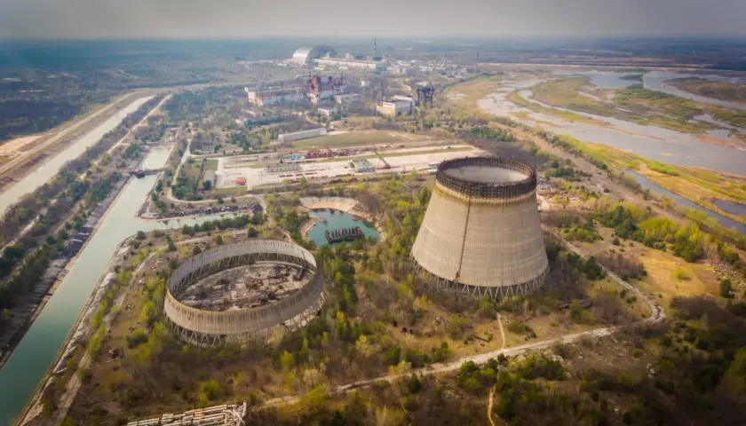 Opuszczone chłodnie kominowe elektrowni atomowej, które miały działać, gdy wybuchł Czarnobyl. W tle widać kompleks budynków i rzekę.