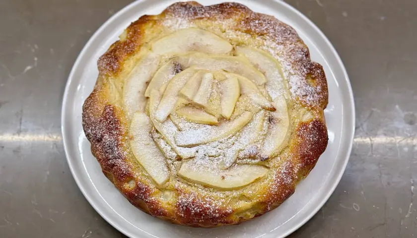Torta ricotta e pere dorata, con fette di pera disposte a raggiera e spolverata di zucchero a velo.