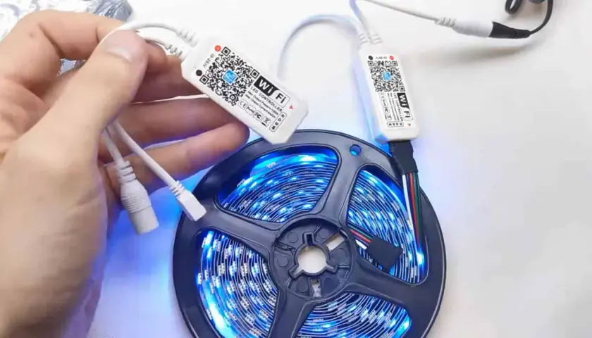 Ręka trzymająca kontroler Wi-Fi do taśmy LED. Dowiedz się, jak zresetować pilot do ledów, skanując kod QR.