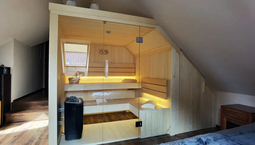 Nowoczesna sauna w domu, z przeszklonymi drzwiami i nastrojowym oświetleniem. Idealne miejsce na relaks.