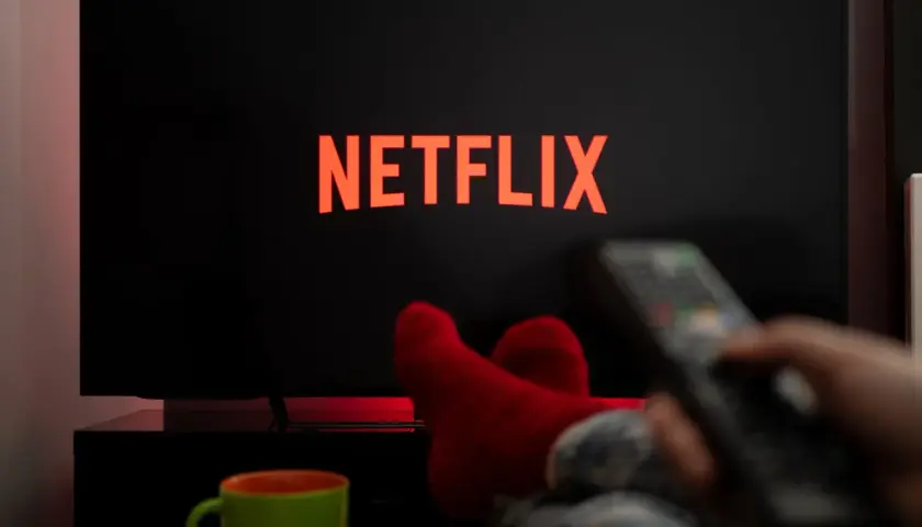 Relaks przy **Netflix w Play**. Czerwone skarpety, kubek i pilot w dłoni zapraszają do seansu.