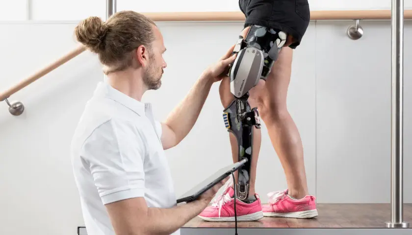 Therapeut passt c-brace an. Voraussetzungen für die Nutzung werden geprüft, während die Person auf einer Holzplattform steht.