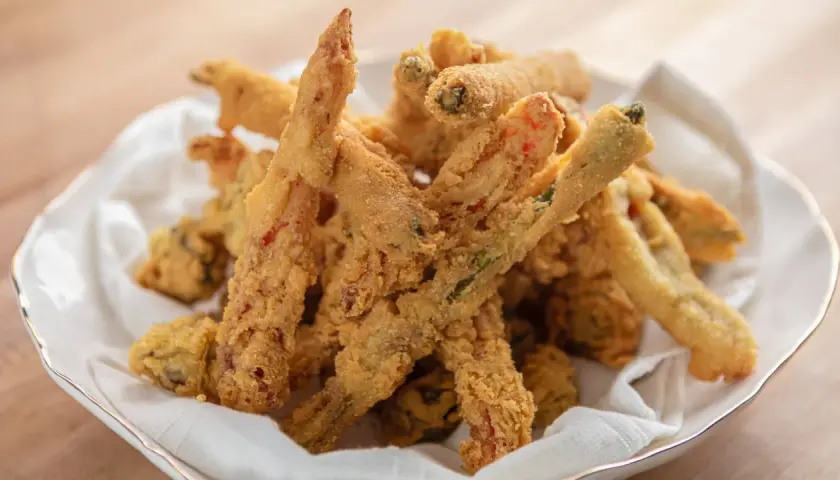 Crispy, golden-brown vegetable sticks coated in a light, airy gluten free tempura batter, served in a white bowl lined with a napkin.